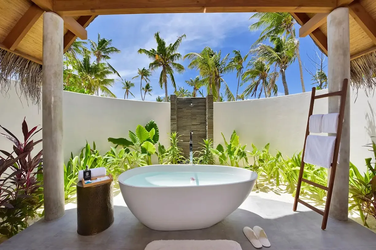 Baño exterior con bañera exenta entre vegetación